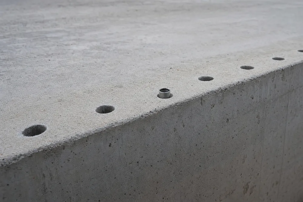 The edge of a concrete block with a row of drilled holes along its top and a steel ring fitted in one of them — resin injection, Newcastle. Illustrative example.